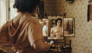 A young woman adjusts her crop top in front of a mirror.